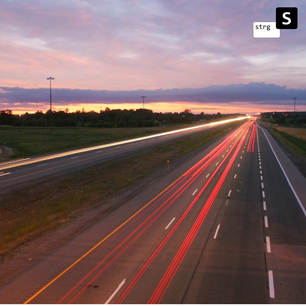 Ein Langzeitbelichtungsfoto einer Autobahn in der Abenddämmerung, das die verschwommenen roten und weißen Lichtspuren der Fahrzeuge mit einem bunten Himmel, Wolken und entfernten Bäumen im Hintergrund einfängt, ähnelt der Essenz von „Fahrtkosten (je KM)“.